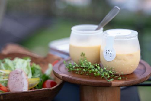 two jars of food on a wooden plate with a salad at くじゅう花公園 グランピングパーク花と星 in Kuju