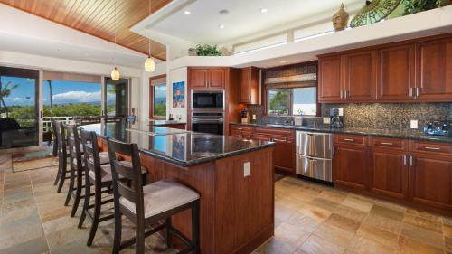 a kitchen with wooden cabinets and a island with bar stools at SUNSET VILLA Spacious Mauna Lani 3BR Home With Private Beach Club in Waikoloa