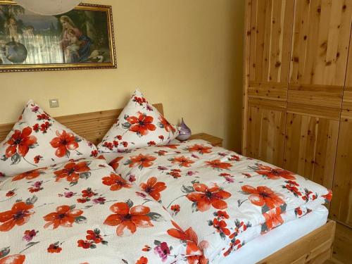 a bed with red flowers on it in a bedroom at FeWo Auszeit Andreas Schreiner in Arrach