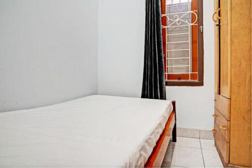 a bedroom with a white bed and a window at Hotel O Penginapan Hj Lilis 2 Syariah in Sukabumi