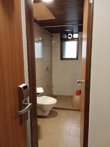 a bathroom with a toilet and a window at Sai Palace Express(Shirdi) in Shirdi