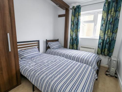 Dos camas una al lado de la otra en un dormitorio. en Beachcombers, 13 Chesil House, en Bridport
