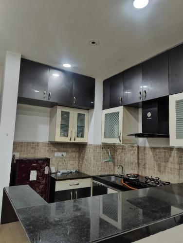 a kitchen with black cabinets and black counter tops at Aasra in Dehu Road