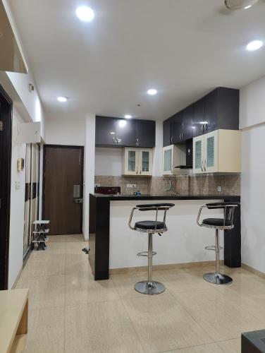 a kitchen with black and white cabinets and bar stools at Aasra in Dehu Road