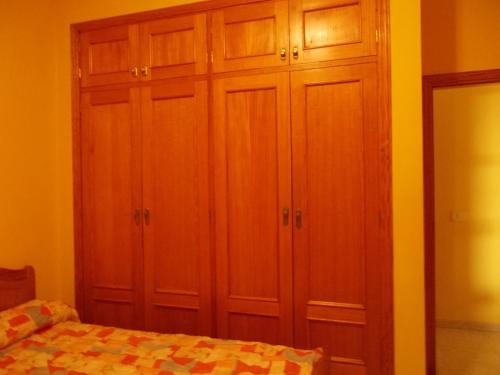 a bedroom with wooden cabinets and a bed at Apartamentos La Banda in Playa de Santiago