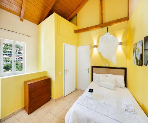a bedroom with a large bed with yellow walls at Almondtree House Exanthia - Private Parking in Exanthia