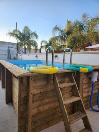 Una mesa de madera con dos trampolines encima, junto a una piscina. en Villa Malese, en Porto Cesareo