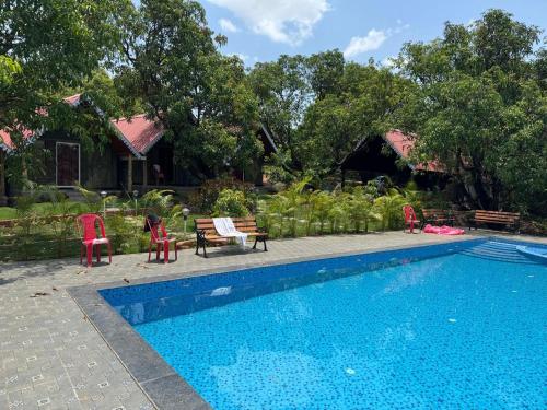 a swimming pool with chairs and a table and a house at Trio Farm serenity home vibe in Sawantwadi