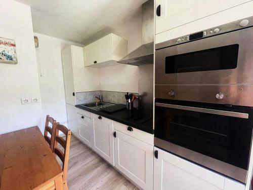 une cuisine avec des armoires blanches et un four noir dans l'établissement Résidence Arc En Ciel C - Appartement de charme pour 4 personnes idéalement situé dans un secteur calme proche des pistes MAE-5561, à Vénosc