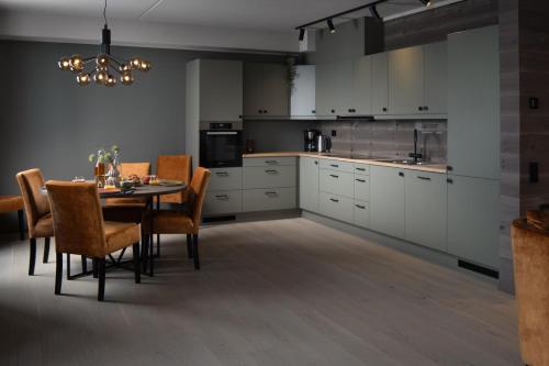 a kitchen with a table and chairs and white cabinets at Riddergaarden Mountain Lodge, Beitostølen in Beitostøl