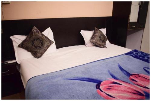 a bed with three pillows on top of it at HOTEL DS STAY VARANASI ! - Near Kasi Vishwanath Temple And Ganga Ghat #Fully Air Conditioning #Free Wi-Fi #Parking #Room Service #Prime Location - Best Selling Premium Hotel in Varanasi in Varanasi