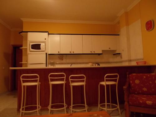 a kitchen with a bar with stools and a microwave at Apartamentos La Banda in Playa de Santiago