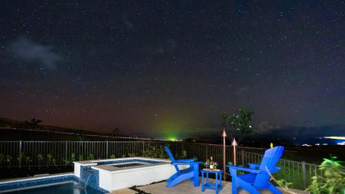 a patio with two chairs and a pool at night at BLUE SERENITY Luxurious home in private community with Heated Private Pool Spa Detached Ohana Suite in Waimea