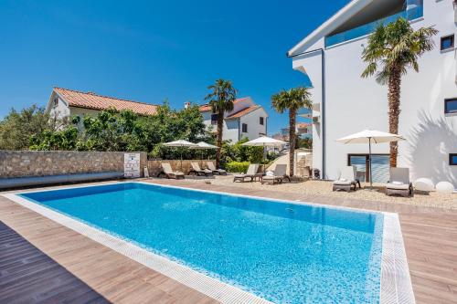 a swimming pool in front of a villa at Villa Palma Krk Penthouse apartment with sea view and private jacuzzi in Krk