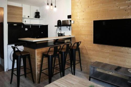 Il comprend une cuisine avec un bar avec des tabourets et une télévision à écran plat. dans l'établissement Résidence L'oustal - Joli studio 4 personnes MAE-2774, aux Orres