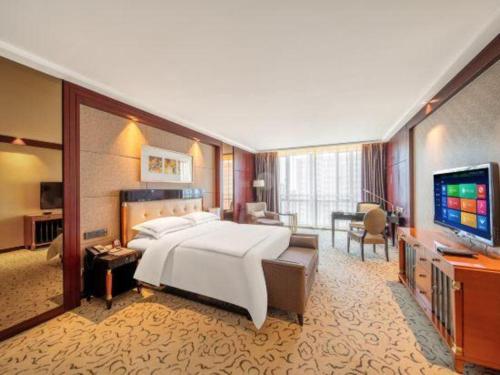 a hotel room with a large bed and a television at Northwest Petroleum Hotel in Ürümqi