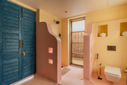 a bathroom with a blue door and a toilet at Luxury Villa With Private Pool, 4-BHK, Assagao in Assagao