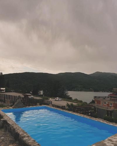 a large blue swimming pool with a view of a lake at Smeštaj Popović in Perućac