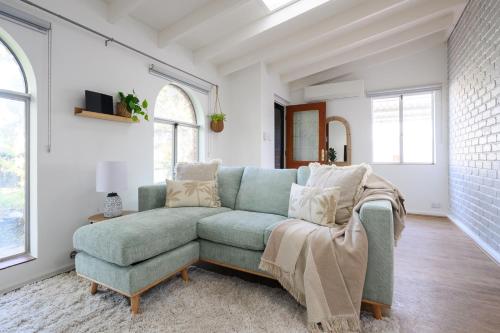 a living room with a green couch and windows at 5 Beach Baby Bungalow & Parking in Perth
