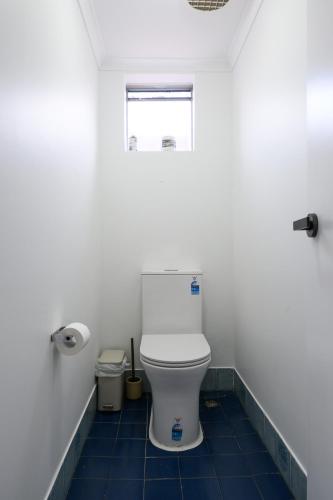 a white toilet in a bathroom with blue tiles at 5 Beach Baby Bungalow & Parking in Perth