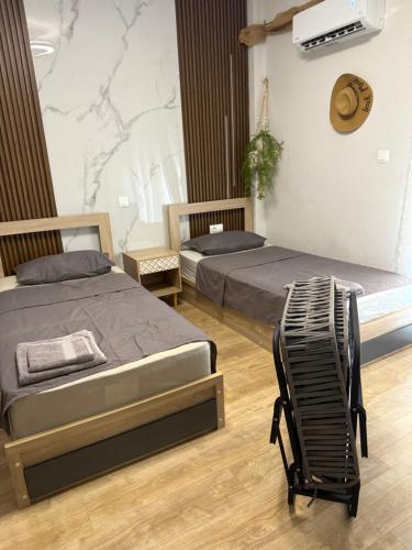 a bedroom with two beds and a chair at Theia Analipsi Central Apartment Katerini in Katerini