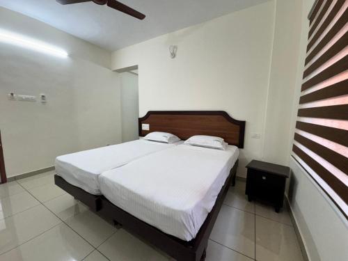 a bedroom with a large bed with white sheets at Sri Gavuri Nivas in Trivandrum