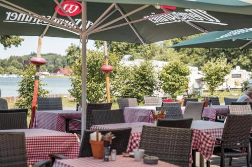 a group of tables and chairs with umbrellas at TinyHouse "Comet" am See, an der Mecklenburger Seenplatte in Fürstenberg-Havel