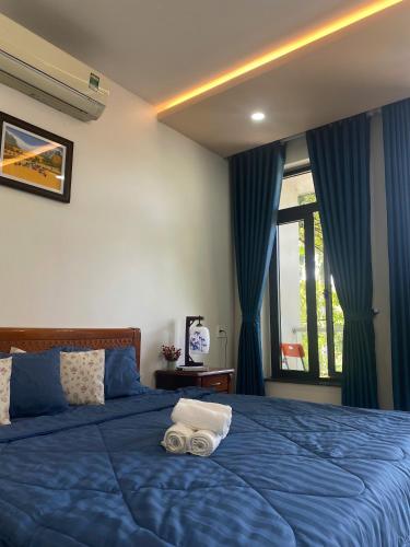 a bedroom with a blue bed with two towels on it at Cibi's Homestay - Tra Khuc riverside in An Bình (1)