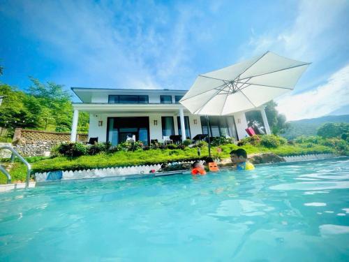 two children in a swimming pool with an umbrella at K Villa - Venuestay in Kệ Sơn