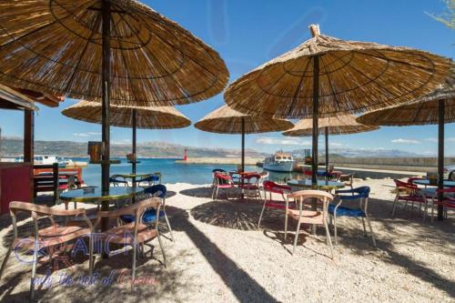 eine Gruppe von Tischen und Stühlen unter Sonnenschirmen am Strand in der Unterkunft Apartment Capitano in Slatine