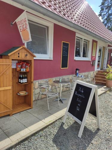 Un restaurante con un cartel delante de un edificio. en Minihotel "Hobbit Town" am See an der Mecklenburger Seenplatte, Schlaffass, en Fürstenberg-Havel