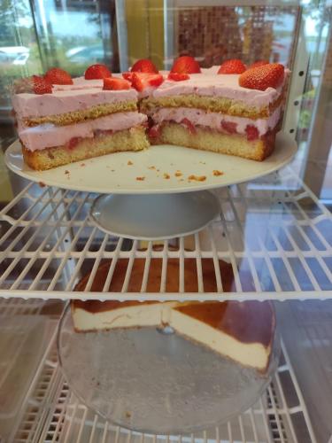 Un pastel de tres capas con fresas encima en el refrigerador. en Minihotel "Hobbit Town" am See an der Mecklenburger Seenplatte, Schlaffass, en Fürstenberg-Havel