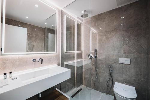 a bathroom with a sink and a shower and a toilet at Boe Luxury Hotel in Sarandë
