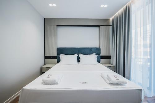 a bedroom with a white bed with two towels on it at Boe Luxury Hotel in Sarandë