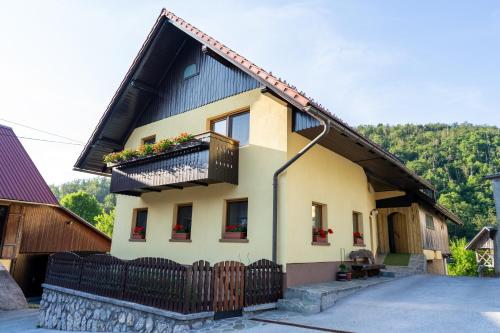 a yellow house with a black roof and a balcony at Sobe na skednju in Bohinjska Bistrica