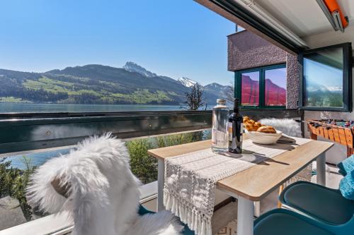 a dog sitting at a table on the balcony of a tiny house at 4 Seasons Apartment I 1-4 Personen I See, Bergsicht I 65'' Smart TV, Tischkicker und Badewanne I Parkplatz in Ingenbohl