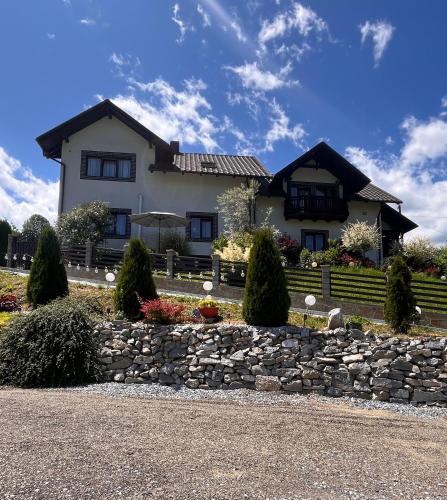 a house with a stone wall in front of it at Casa de pe Deal in Sadova