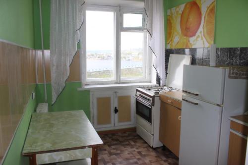 a kitchen with a white refrigerator and a window at Apartments on the River in Kamyshin