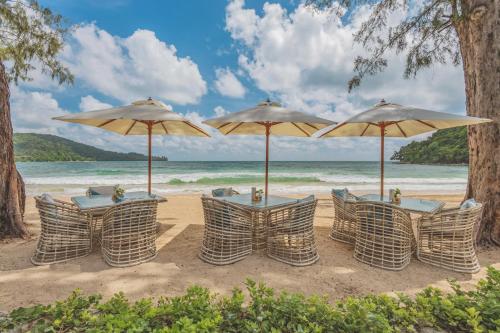 a group of tables and umbrellas on a beach at Twinpalms MontAzure Phuket in Kamala Beach