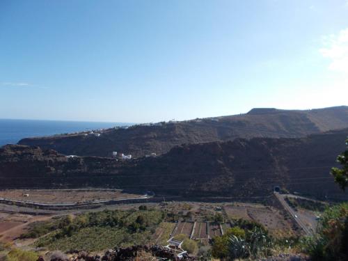 a view of a mountain with the ocean in the background at Apartamentos La Banda in Playa de Santiago