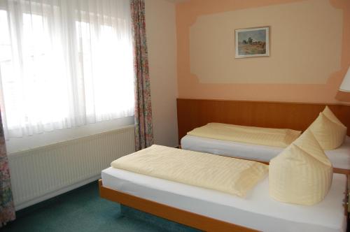 two beds in a small room with a window at Hotel garni St. Marien in Naumburg