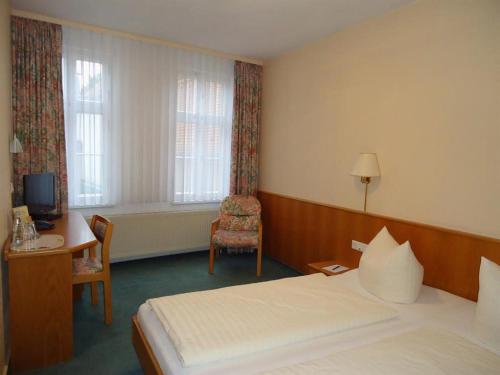 a hotel room with a bed and a chair and a desk at Hotel garni St. Marien in Naumburg