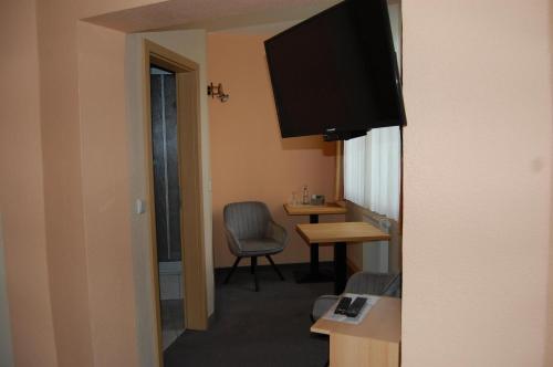 a room with a tv and a chair and a table at Hotel garni St. Marien in Naumburg