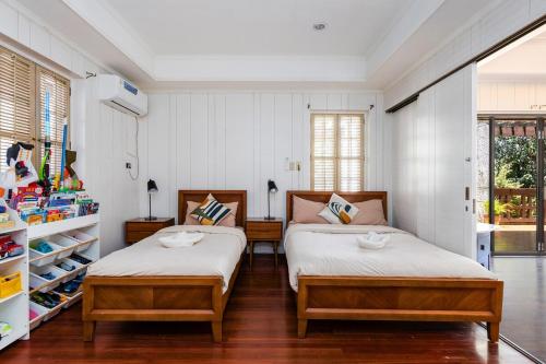 two beds in a bedroom with white walls and wood floors at Private Beach Villa in Anza Mactan with Ocean View in Punta Engaño