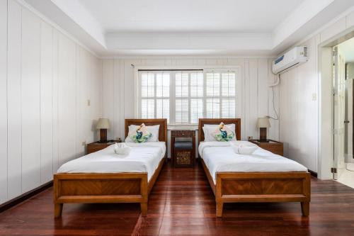 two beds in a room with white walls and wood floors at Private Beach Villa in Anza Mactan with Ocean View in Punta Engaño