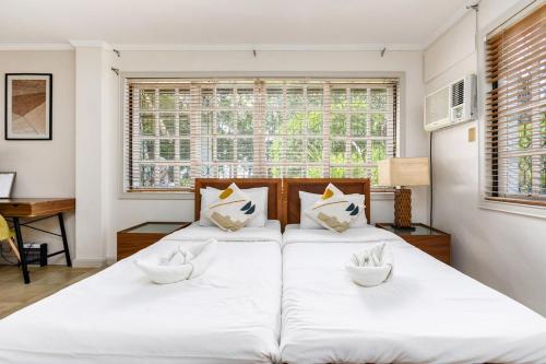 two white beds in a room with a window at Private Beach Villa in Anza Mactan with Ocean View in Punta Engaño