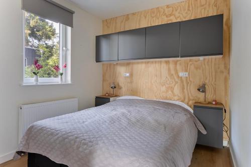 a bedroom with a bed and a wall with a tv at Lodge 't Hert - Nieuwe lodge met vrij uitzicht & omheinde tuin in Putten