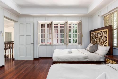 a white bedroom with two beds and a window at Private Beach Villa in Anza Mactan with Ocean View in Punta Engaño