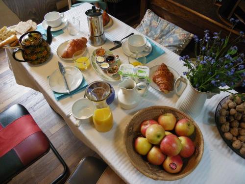 a table with a bowl of apples and orange juice at les couleurs de l'eau in Plonéour-Lanvern