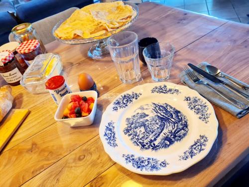 een houten tafel met een bord eten erop bij Chambre d'hôte avec Charme et Jardin in Saint-Rémy-du-Plein